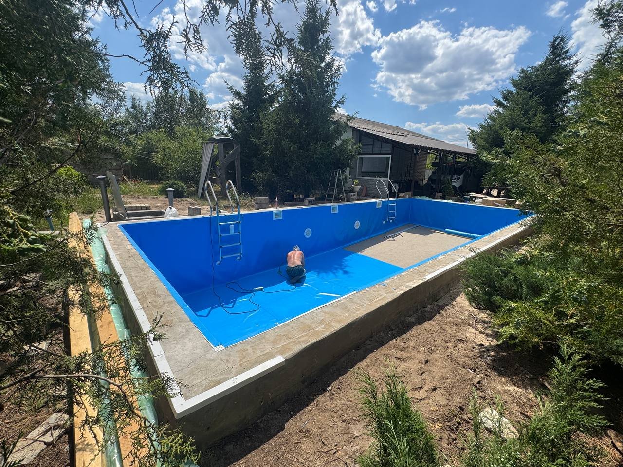 Before — unfinished backyard pool with bare liner and no deck